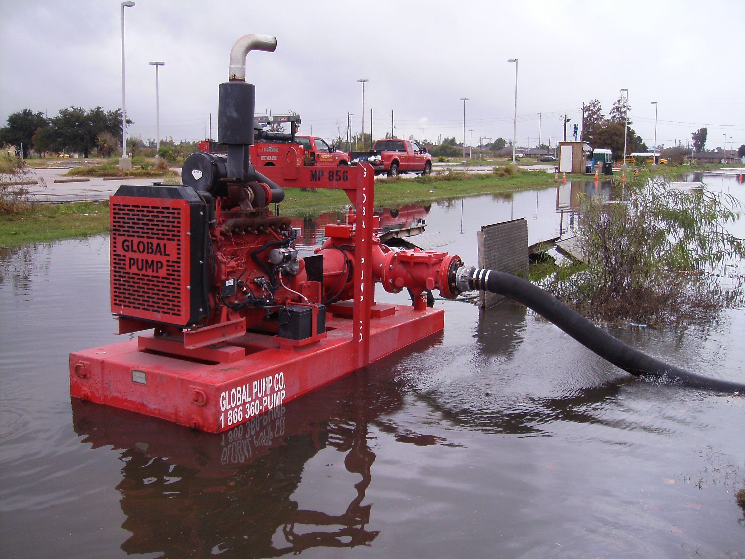 Red pump actively draining floodwater through a large hose situated in submerged area